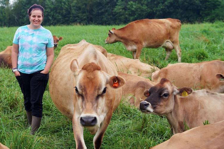 Gillian Newbold stands in a field among the UNH Organic Dairy Research Farm’s Jersey cows.
